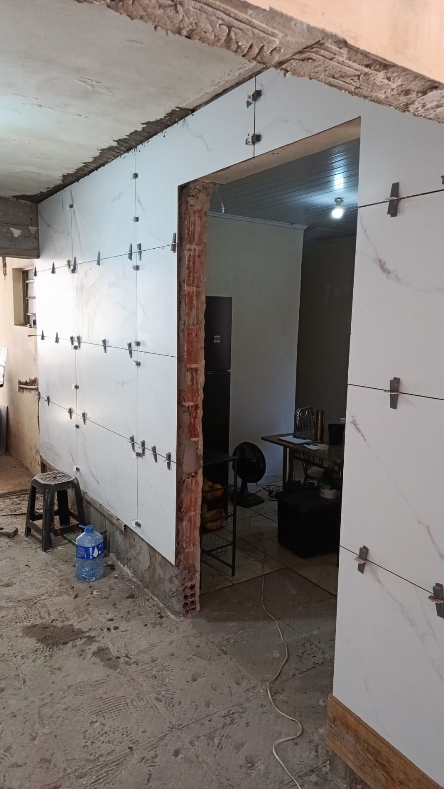 obra em andamento com paredes internas revestidas de porcelanato branco marmorizado,使用的 niveladores plásticos, porta ao 